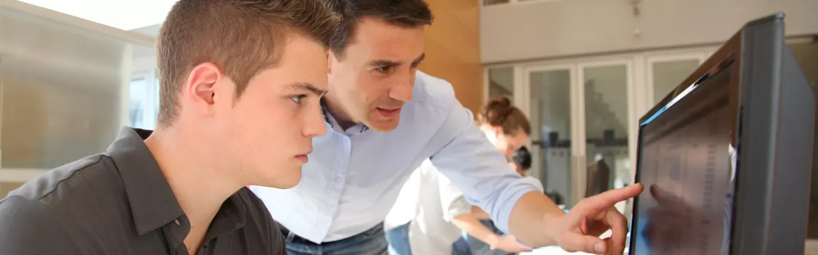 teacher pointing at computer screen with student